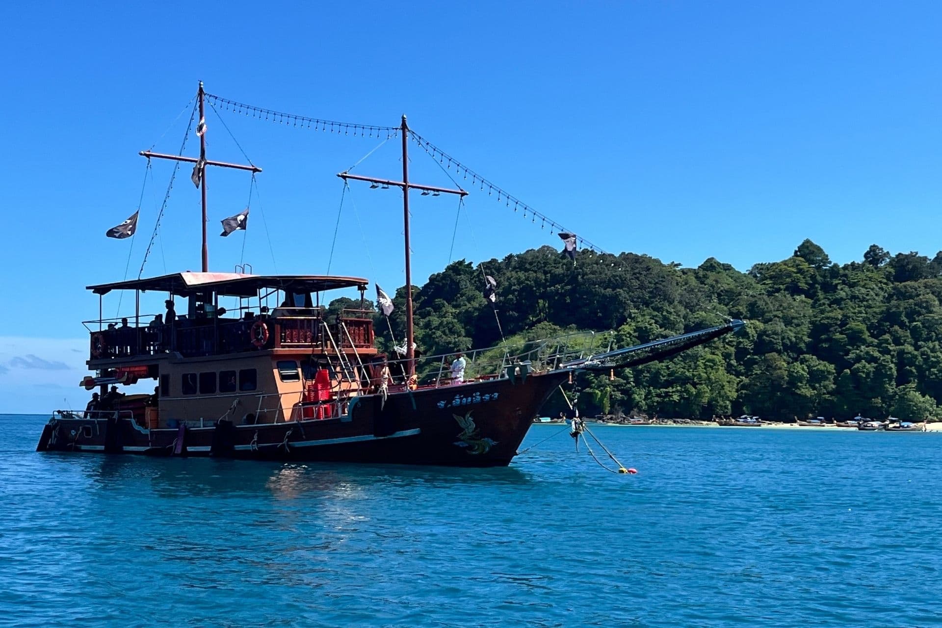 The Phoenix — orange-hulled boat with a golden phoenix figurehead anchored off Phi Phi