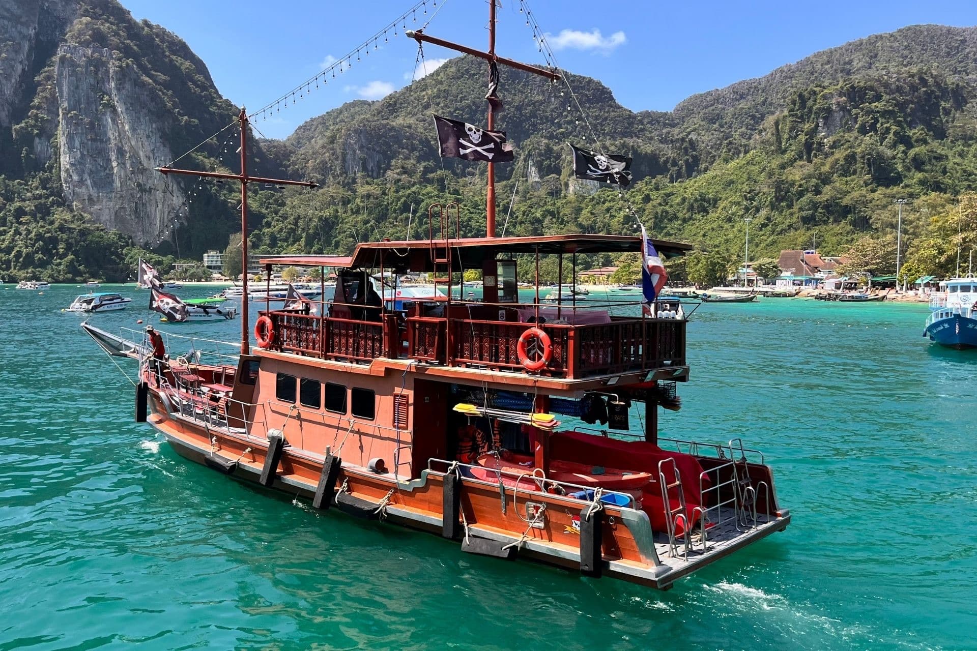 The Dragon moored in turquoise water before the cliffs