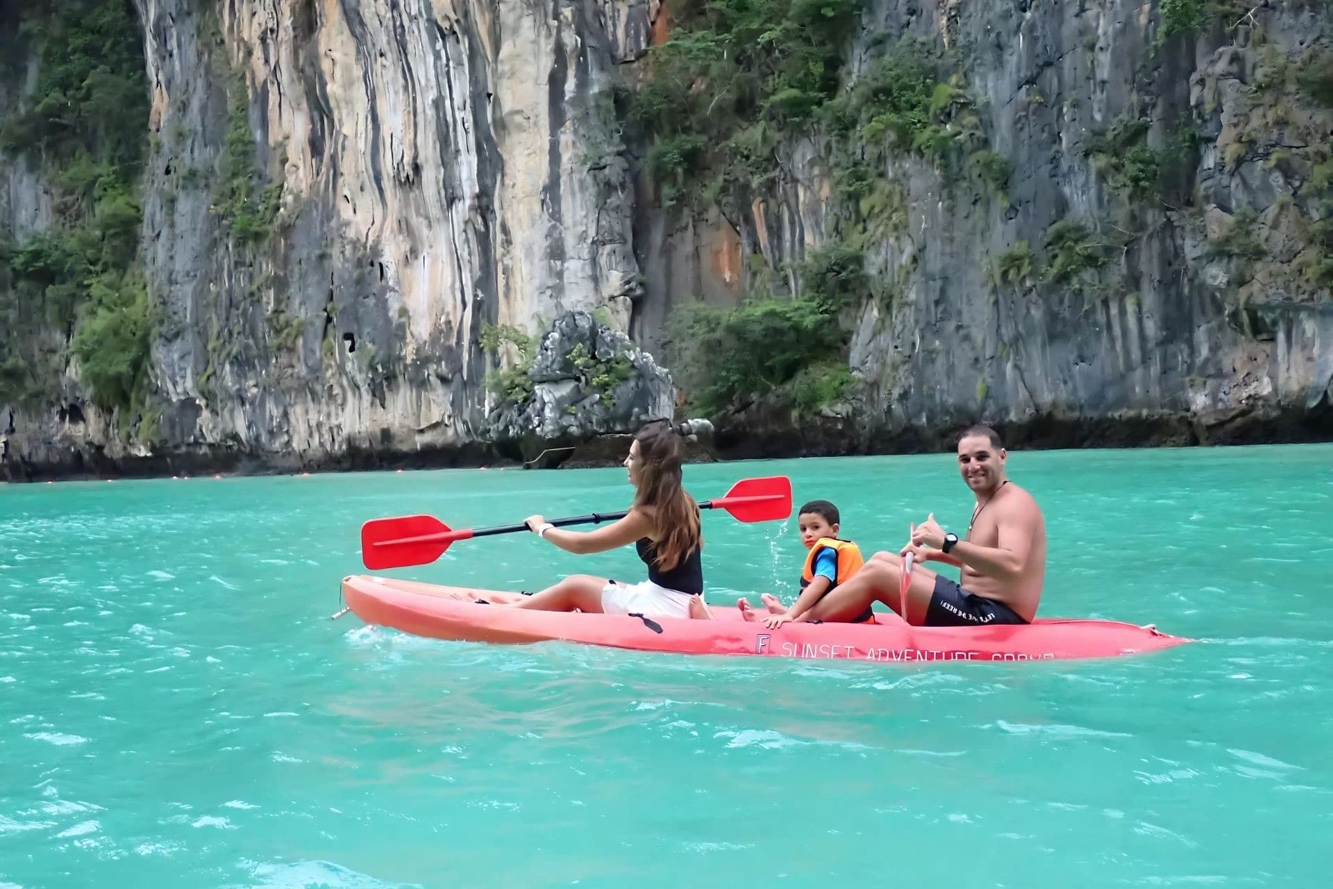 A family kayaking across vivid turquoise water